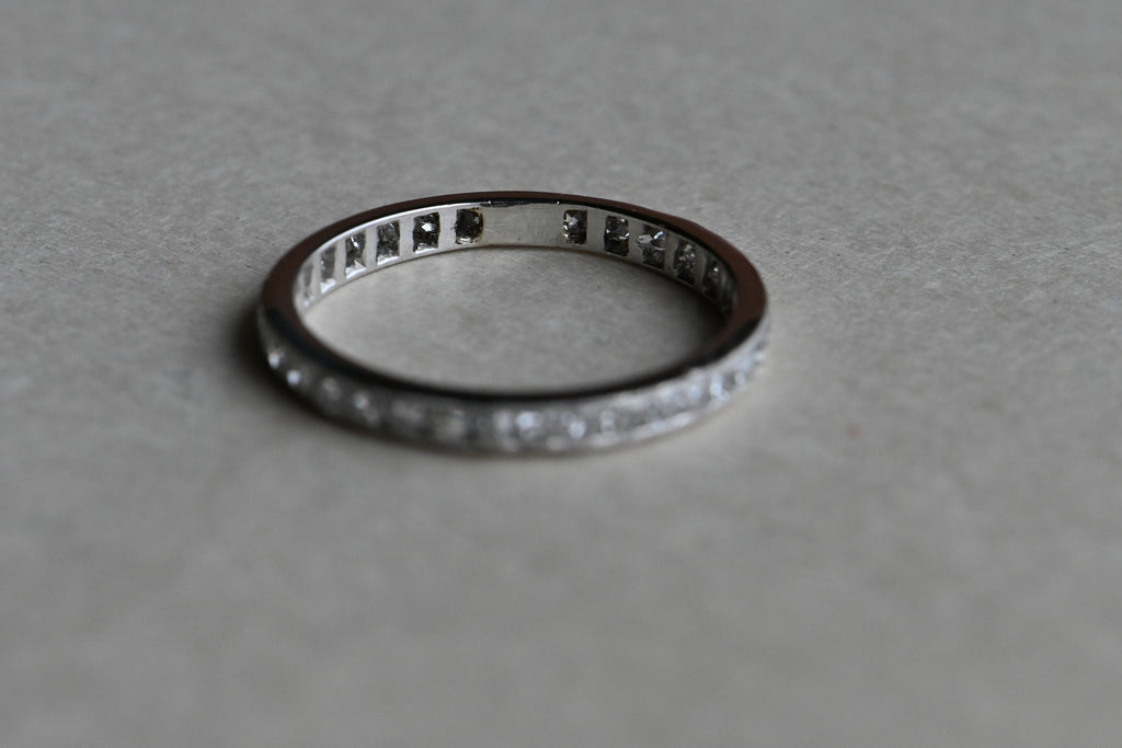 An Art Deco platinum eternity band engraved for a wedding on 4-3-20 … this ring is 102 years old! The band is channel set with thirty-four (34), à joured single cut diamonds, .75 CTW. Milgrain edging and a single "blank" space. Slim and elegant for stacking or pairing with an engagement ring. Engraved on one edge with "W.E.W. Jr. and D.Q. 4-3-20.” Outstanding condition. 