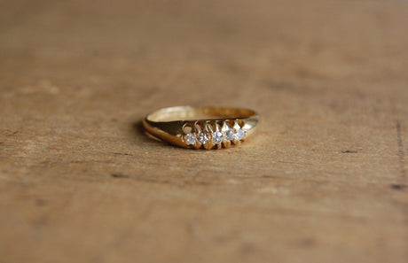 An elegant antique, English engagement ring from the year 1918. The ring is set with a row of five graduated diamonds in an 18K yellow gold setting.